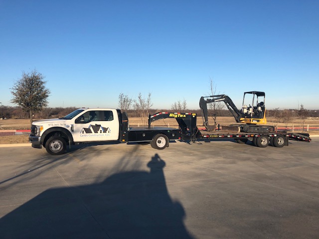 Roof tear-off equipment | Genes Construction Genes Construction roofing truck hauling a mini excavator for tear-off, site work, and roof replacement staging