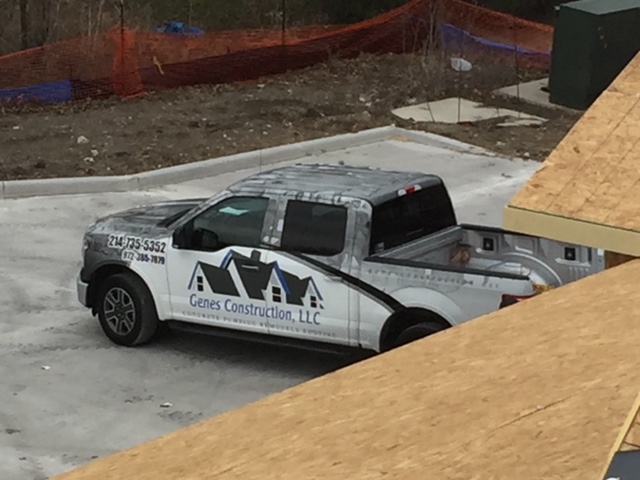 Roofing job-site truck | Genes Construction Genes Construction roofing truck on a new-construction job site beside roof decking in North Texas